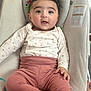 baby, child, infant, sitting, clothing, pink_pants, white_top, face, cute, indoors, cushion, seat, hand, foot, expression, portrait, young, comfortable, looking, person