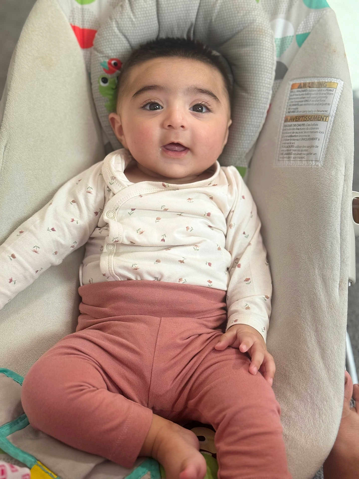 Fatima joined the competition — help win amazing prizes! baby, child, infant, sitting, clothing, pink_pants, white_top, face, cute, indoors, cushion, seat, hand, foot, expression, portrait, young, comfortable, looking, person