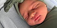 Nova is registered to the contest to win money with this photo: newborn, baby, sleeping, swaddle, headband, hospital, bassinet, infant, peaceful, closeup, cute, resting, soft_lighting, child, portrait, skin, face, wrapped, headwear, indoors