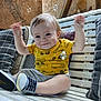 baby, child, smiling, yellow_shirt, sneakers, bench, bubbles, pillow, wooden_bench, indoor, happy, cute, toddler, raising_hands, casual_clothing, plaid_pillow, cushion, wood, playful, portrait