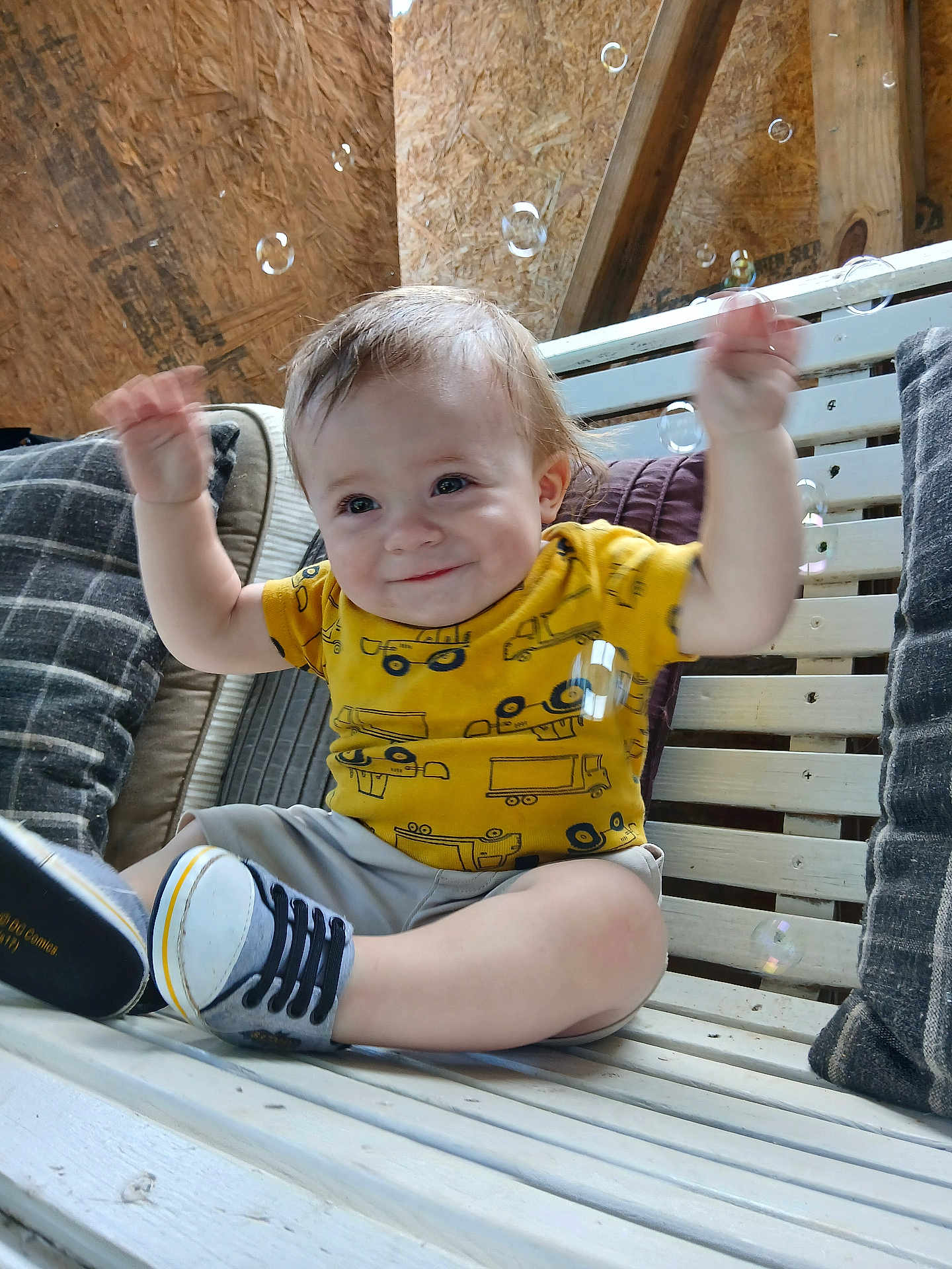 Noah joined the competition — help win amazing prizes! baby, child, smiling, yellow_shirt, sneakers, bench, bubbles, pillow, wooden_bench, indoor, happy, cute, toddler, raising_hands, casual_clothing, plaid_pillow, cushion, wood, playful, portrait