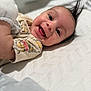 Ashton is registered to the contest to win money with this photo: baby, smiling, infant, lying_down, cute, happy, face, tongue, hair, mohawk, shirt, cartoon_print, texture, white_background, child, portrait, indoors, closeup, person, joy