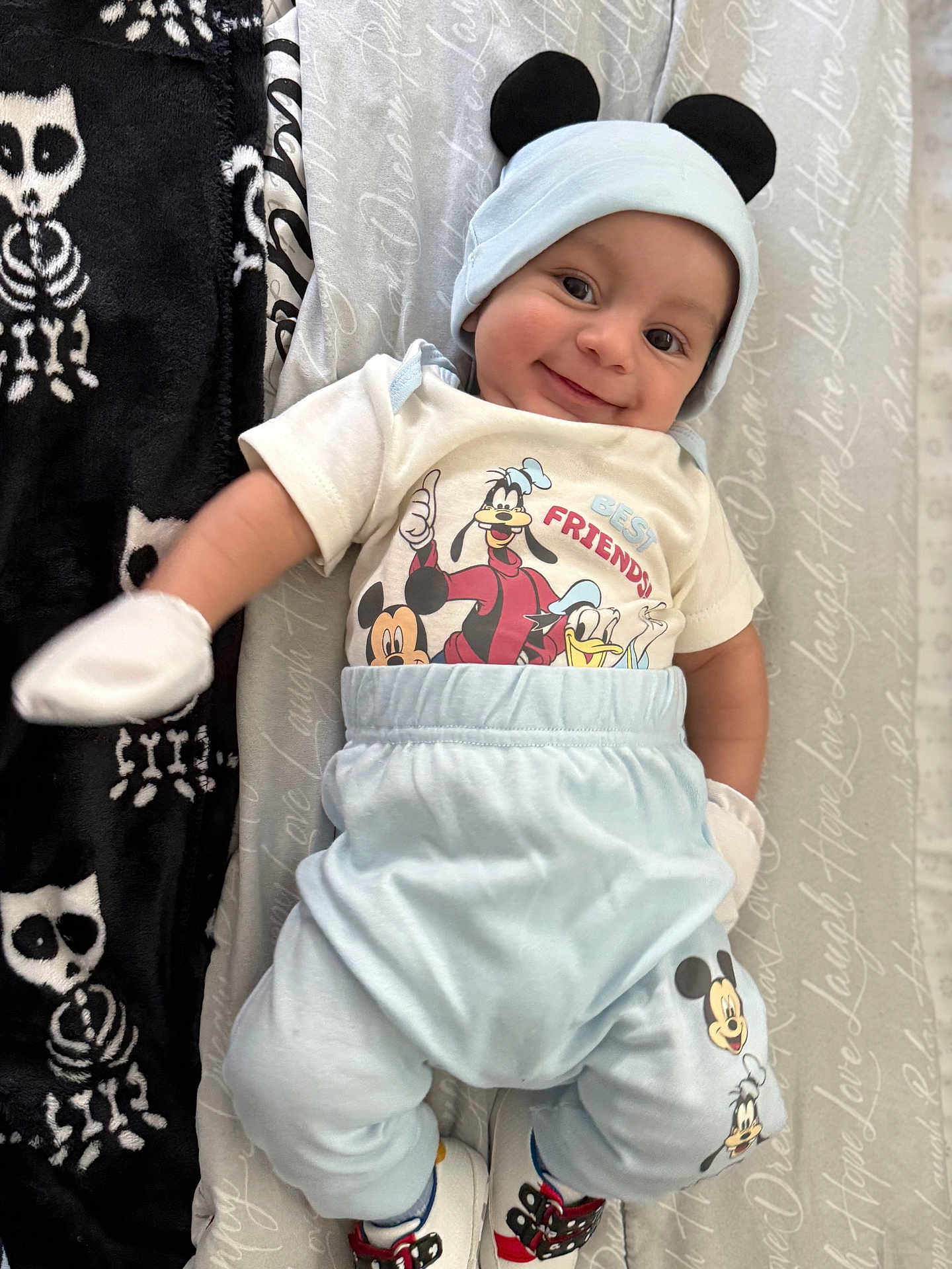 Ashton joined the competition — help win amazing prizes! baby, smiling, infant, mickey_mouse, hat, mittens, blue_pants, white_shirt, cartoon_characters, blanket, lying_down, cute, happy, footwear, soft_toys, patterned_blanket, child, indoors, portrait, clothing