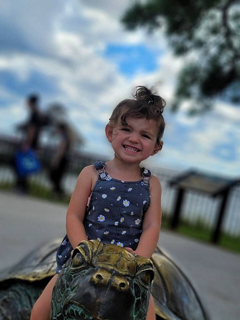 Ariya is registered to the contest to win money with this photo: bag, cloud, eyewear, flash_photography, fun, grass, happy, joy, landscape, leisure, luggage_and_bags, motor_vehicle, pattern, person, plant, recreation, sitting, sky, smile, toddler