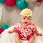 Wrenleigh is registered to the contest to win money with this photo: baby, infant, child, portrait, sitting, smiling, wide_eyes, flower_headband, dress, pink_clothing, balloons, birthday, celebration, colorful, indoor, blanket, bed, baby_photography, festive, cute