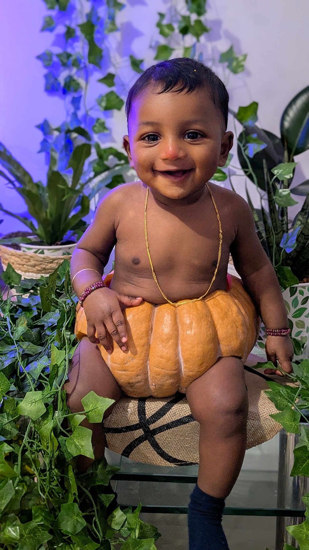 Aro a rejoint le concours — aidez-le/la à gagner de superbes lots ! baby, child, pumpkin, smiling, plants, greenery, jewelry, bracelets, indoor, portrait, cute, happy, sitting, decor, leaves, gold_necklace, dark_skin, short_hair, sock, closeup