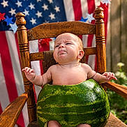 Ivar joined the competition — help win amazing prizes! baby, child, watermelon, wooden_chair, american_flag, stars, outdoor, summer, cute, funny_expression, fruit_costume, patriotic, green, red, blue, wood, skin, face, sitting, holiday
