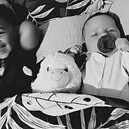 Thomas joined the competition — help win amazing prizes! baby, infant, child, smile, pacifier, blanket, plush_toy, cow_plush, bed, pillow, sleepwear, happy, cute, indoor, portrait, toddler, resting, black_and_white, siblings, cozy