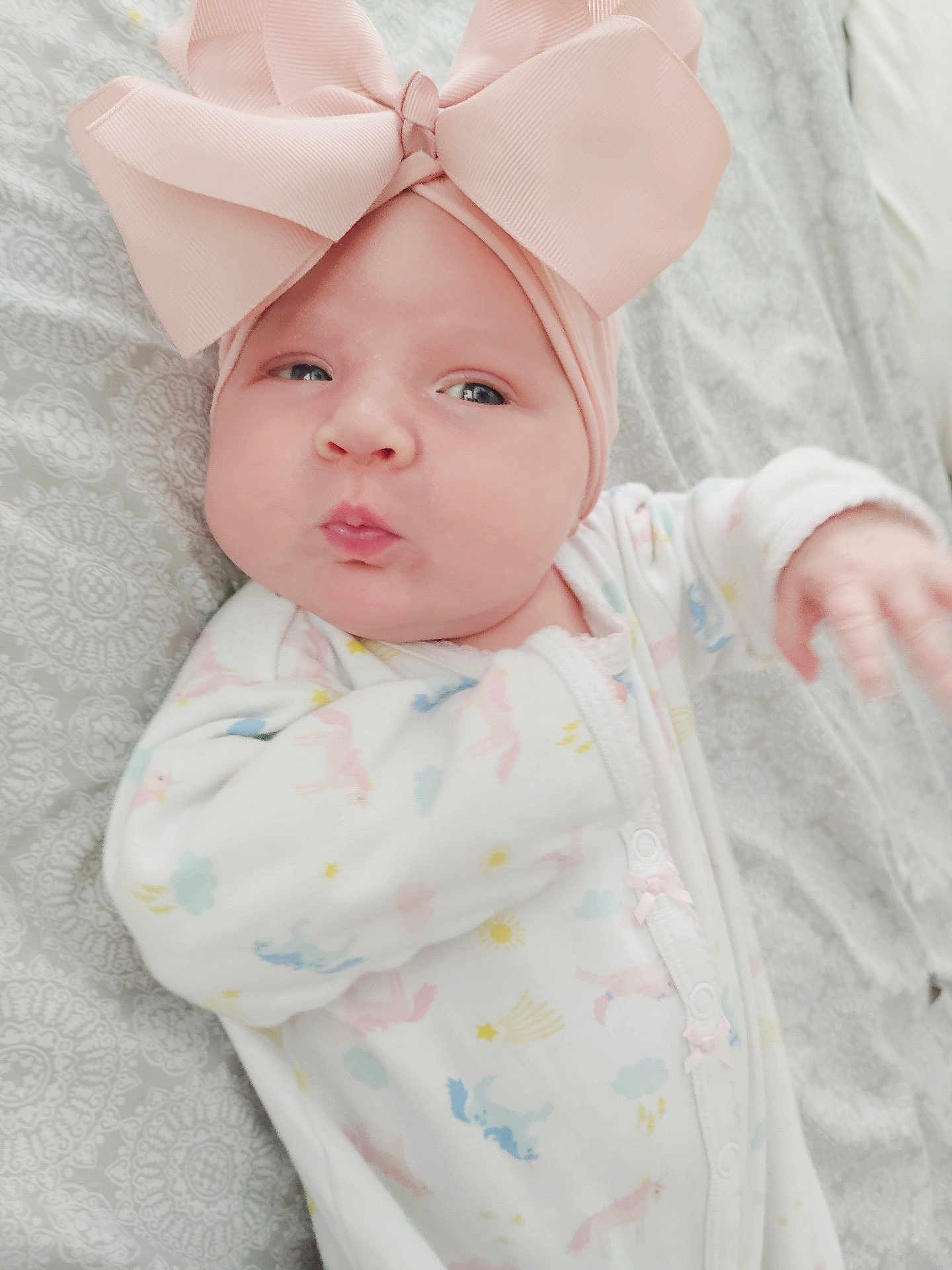 Nova joined the competition — help win amazing prizes! baby, infant, pink_bow, headband, onesie, puckered_lips, cute, lying_down, blanket, patterned_blanket, pastel_colors, hand, face, cheeks, sleepwear, soft_lighting, indoors, child, adorable, newborn