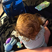 Lyra joined the competition — help win amazing prizes! baby, curly_hair, toys, blanket, indoor, cooler_bag, wipes, infant, child, floor, blue, purple, green, soft_toy, cute, top_view, legs, skin, relaxed, casual