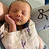 newborn, baby, sleeping, blanket, lavender_pattern, hand, face, peaceful, closeup, infant, cute, soft, wrapped, resting, person, skin, nap, cozy, portrait, indoors