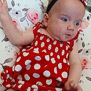 Alaya is registered to the contest to win money with this photo: baby, child, clothing, cute, drool, face, floral_pattern, hand, headband, indoor, infant, person, pillow, polka_dot, portrait, red_dress, sitting, skin, smile, young_child