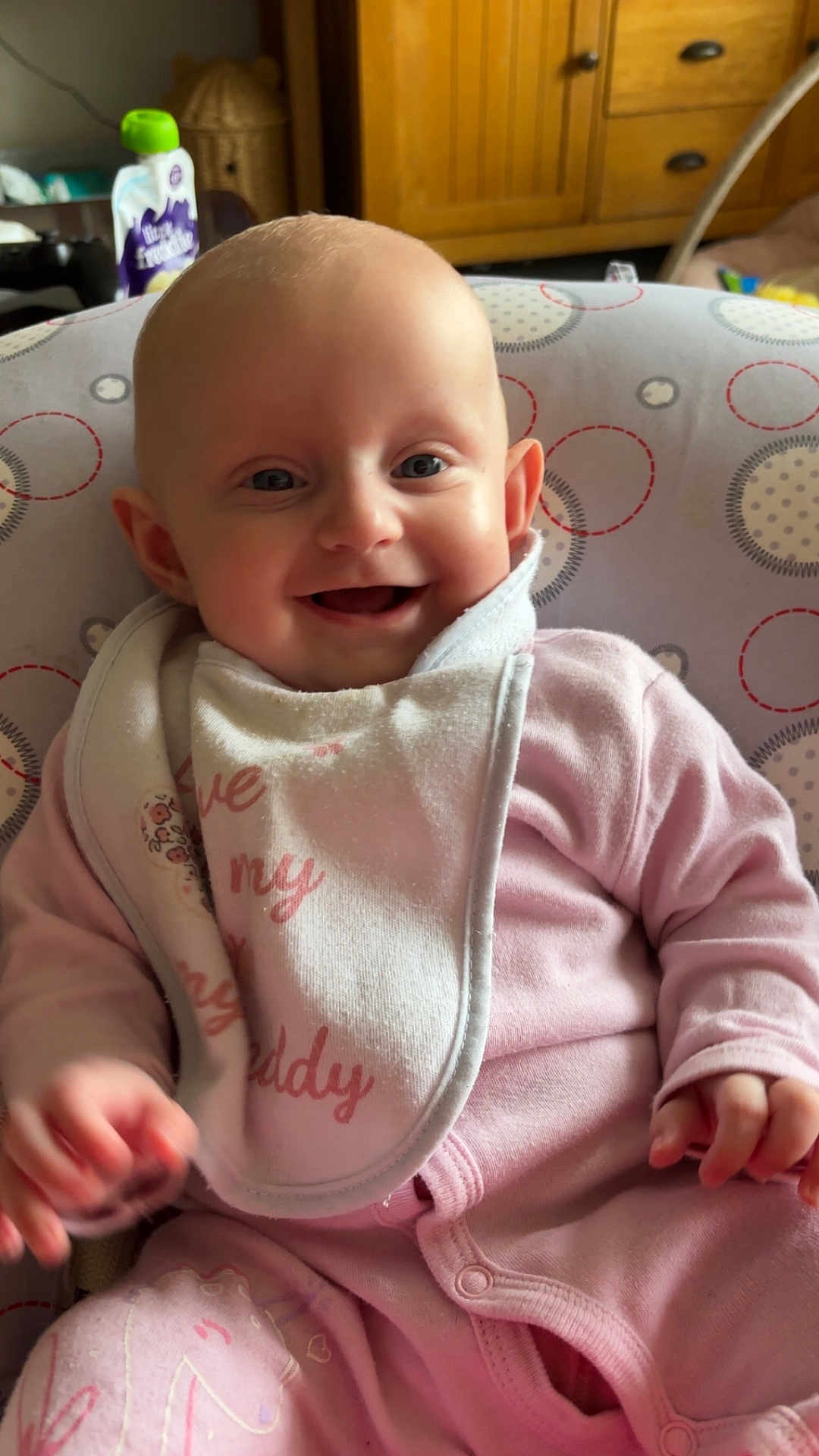 Arabella joined the competition — help win amazing prizes! baby, smiling, pink_pajamas, bib, child, infant, face, happy, sitting, indoor, furniture, home, cute, pattern, unicorn, hand, head, eyes, clothing, person