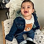 baby, denim_jacket, smiling, child, cute, indoor, cushion, star_pattern, clothing, portrait, happy, infant, socks, face, seated, wooden_frame, casual_wear, toddler, expression, cozy