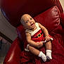 baby, infant, child, red_chair, knit_dress, white_socks, smiling, happy, seated, indoors, plush, holiday_outfit, cute, portrait, young_child, cozy, red_blanket, skin, face, person