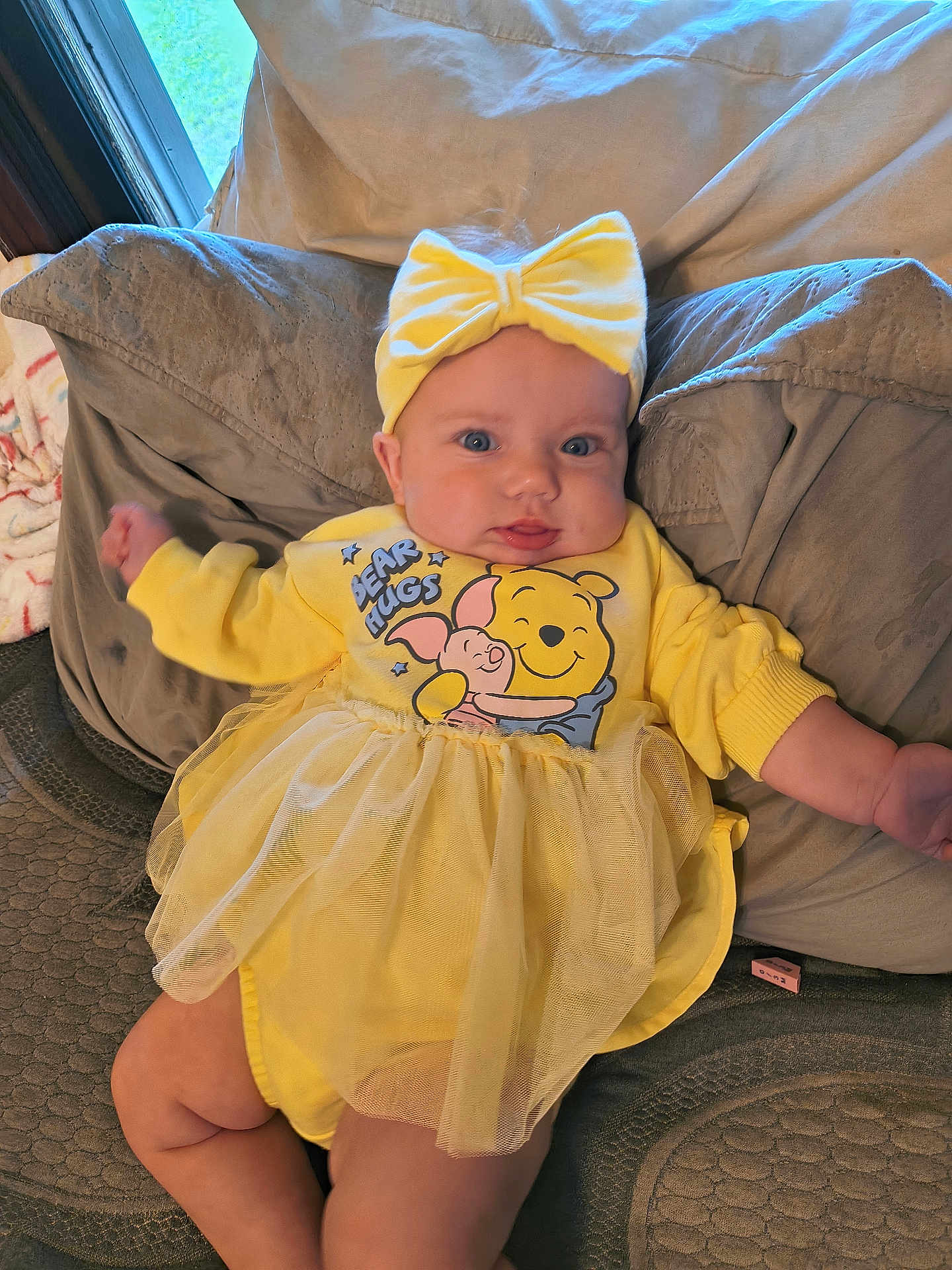 Ariel joined the competition — help win amazing prizes! baby, yellow, headband, bow, couch, cushion, infant, child, tutu, dress, winnie_the_pooh, bear_hugs, blue_eyes, indoor, portrait, cute, smiling, plush, window, relaxed