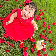 Daphne Zeinet is registered to the contest to win money with this photo: baby, child, red_dress, grass, rose_petals, smiling, outdoor, celebration, cake, footwear, happy, portrait, cute, person, nature, accessory, jewelry, sitting, headwear, festive
