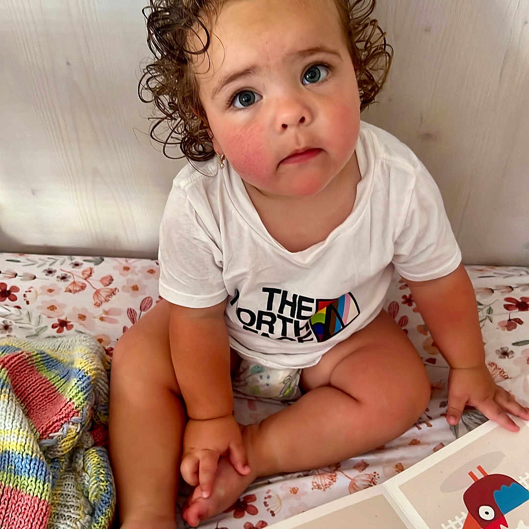 Everleigh joined the competition — help win amazing prizes! baby, bed, bedroom, bodypart, clothing, computer, electronics, face, finger, furniture, hand, head, indoors, person, photography, portrait, reading, room, sitting, t_shirt