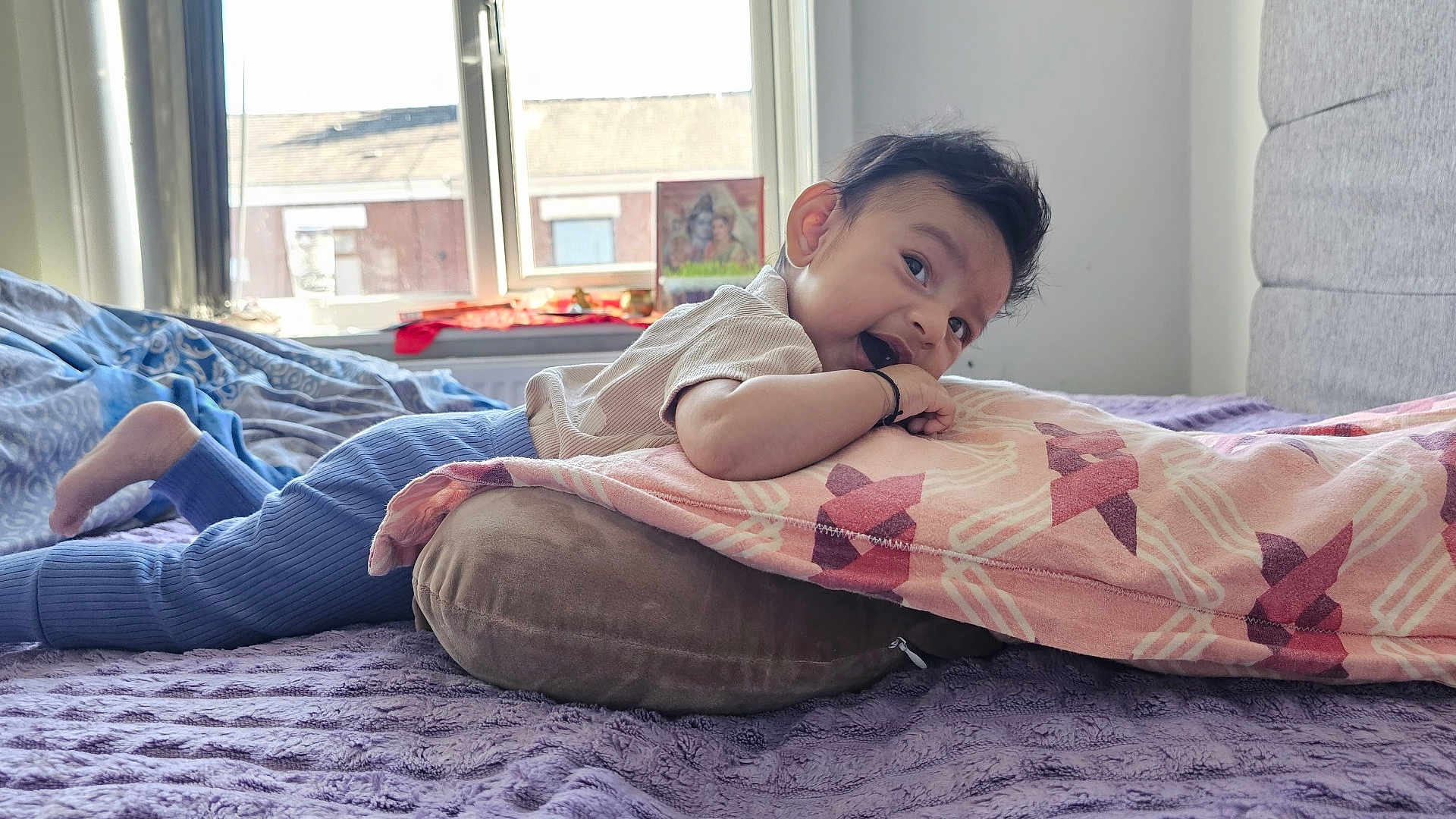 Shrivika is registered to the contest to win money with this photo: baby, bed, blanket, child, clothing, cozy, curtains, cushion, face, happy, head, indoor, light, person, pillow, purple_bedspread, resting, smile, window, young