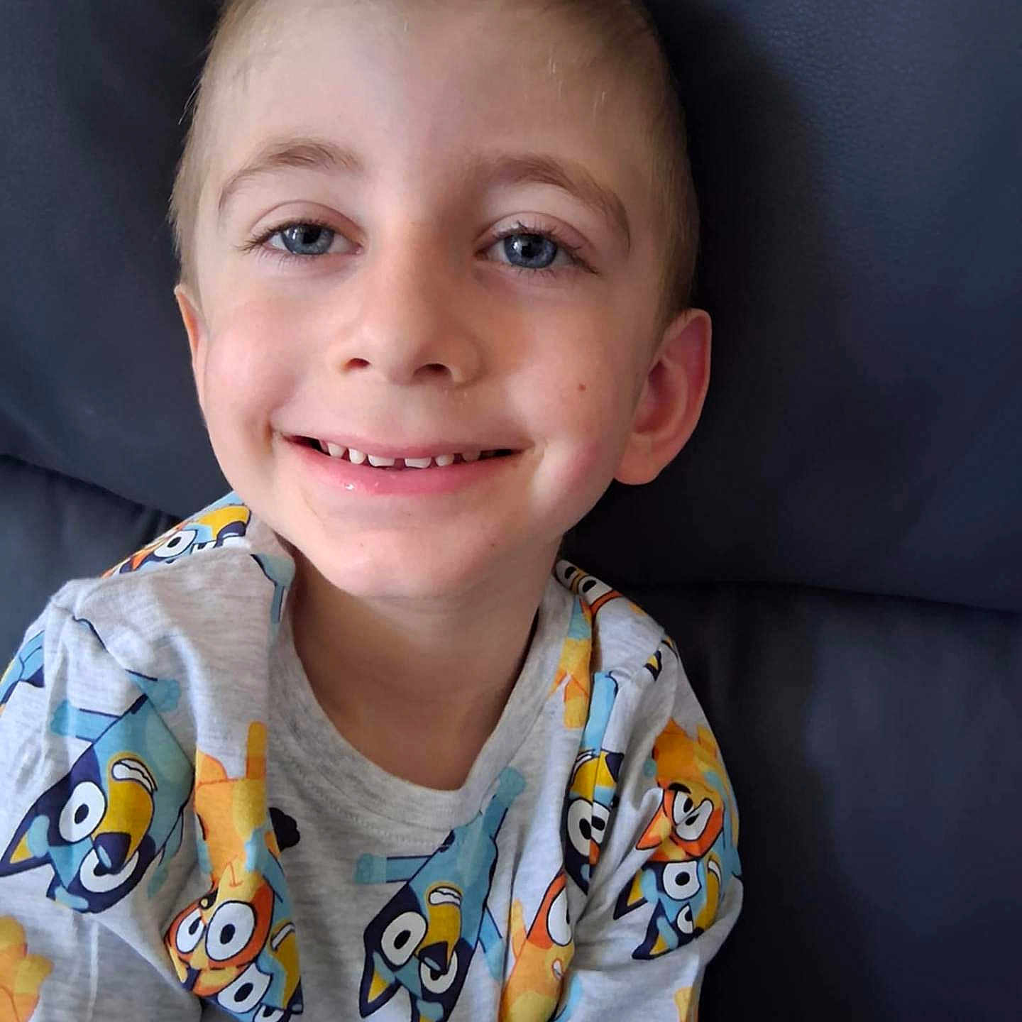 Justin a rejoint le concours — aidez-le/la à gagner de superbes lots ! blue_eyes, boy, cartoon_shirt, casual_wear, child, closeup, colorful_clothing, cute, face, happy, indoors, joyful, light_skin, person, portrait, relaxed, short_hair, sitting, smiling, youth