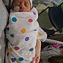 Khyyler is registered to the contest to win money with this photo: newborn, baby, swaddled, blanket, polka_dot, hospital, hat, medical_patch, sleeping, infant, hand, adult, child, chair, indoor, family, person, cozy, colorful, resting