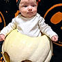 baby, pumpkin, halloween, headband, white_clothing, orange, black_background, stars, jack_o_lantern, hollow_pumpkin, infant, costume, cute, holiday, decor, face, sitting, child, portrait, festive