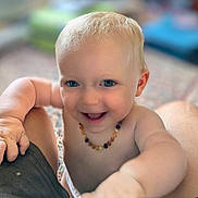 Nina a rejoint le concours — aidez-le/la à gagner de superbes lots ! baby, child, blue_eyes, smiling, bare_chest, necklace, arm, hand, indoor, blurred_background, happy, cute, infant, skin, person, portrait, closeup, toddler, playing, expression
