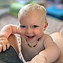 baby, child, blue_eyes, smiling, bare_chest, necklace, arm, hand, indoor, blurred_background, happy, cute, infant, skin, person, portrait, closeup, toddler, playing, expression