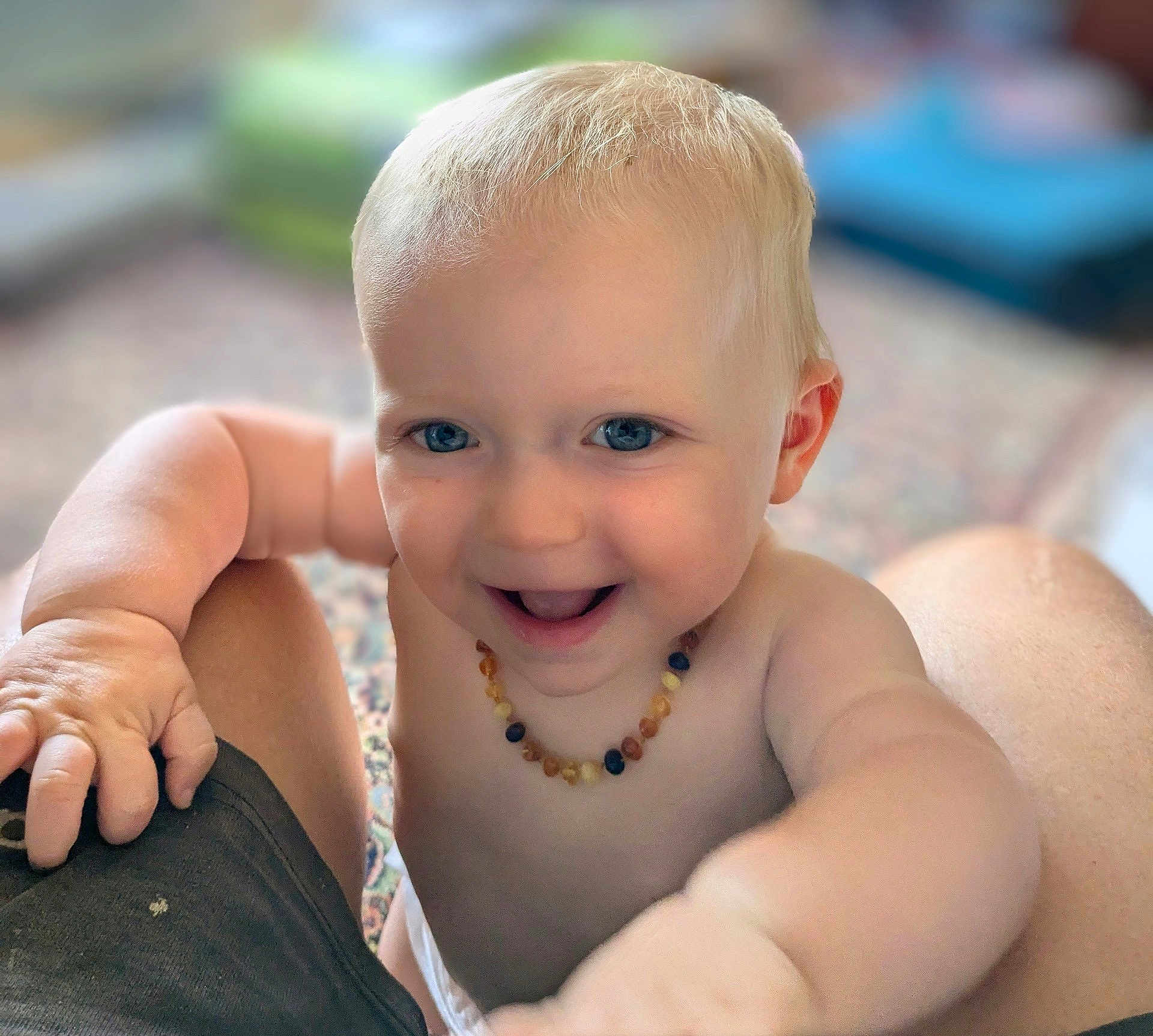 Nina a rejoint le concours — aidez-le/la à gagner de superbes lots ! baby, child, blue_eyes, smiling, bare_chest, necklace, arm, hand, indoor, blurred_background, happy, cute, infant, skin, person, portrait, closeup, toddler, playing, expression