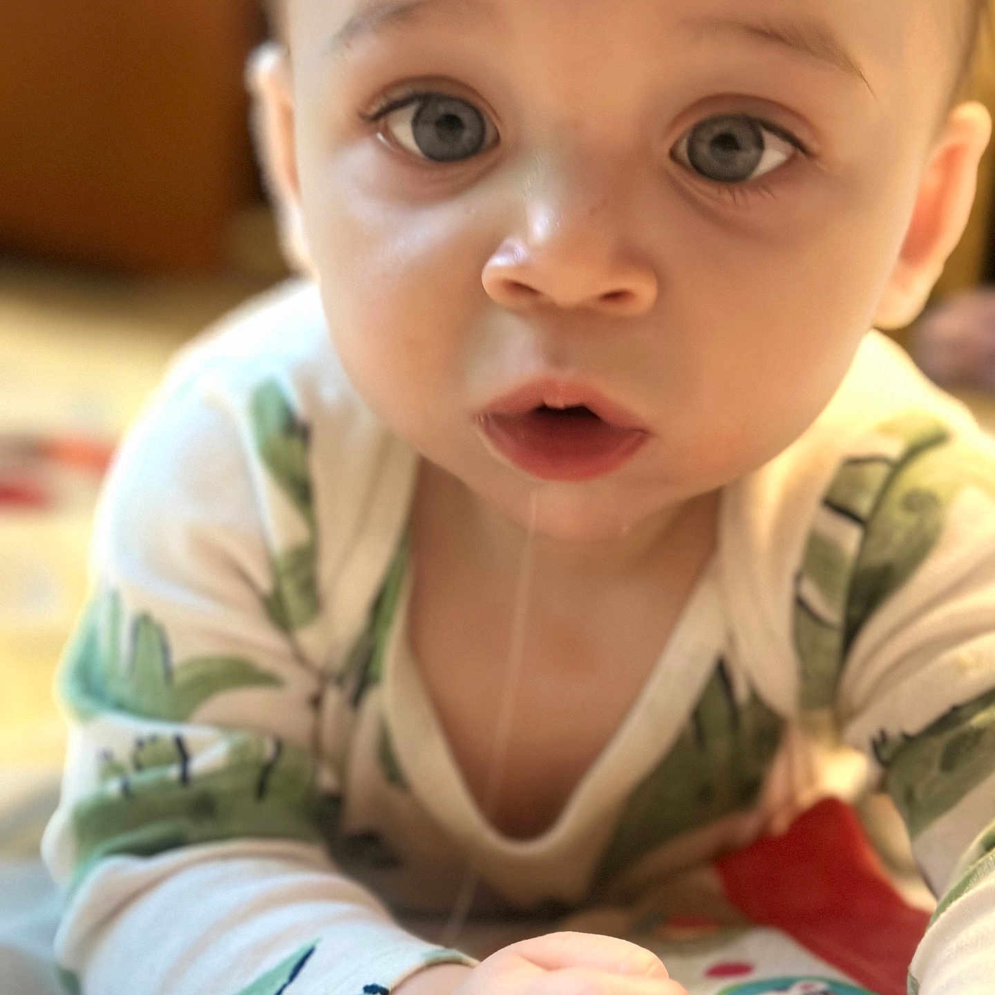 Idris is registered to the contest to win money with this photo: baby, blue_eyes, child, closeup, crawling, curious, cute, drool, expression, face, hand, indoor, infant, onesie, person, play_mat, portrait, skin, soft_light, young