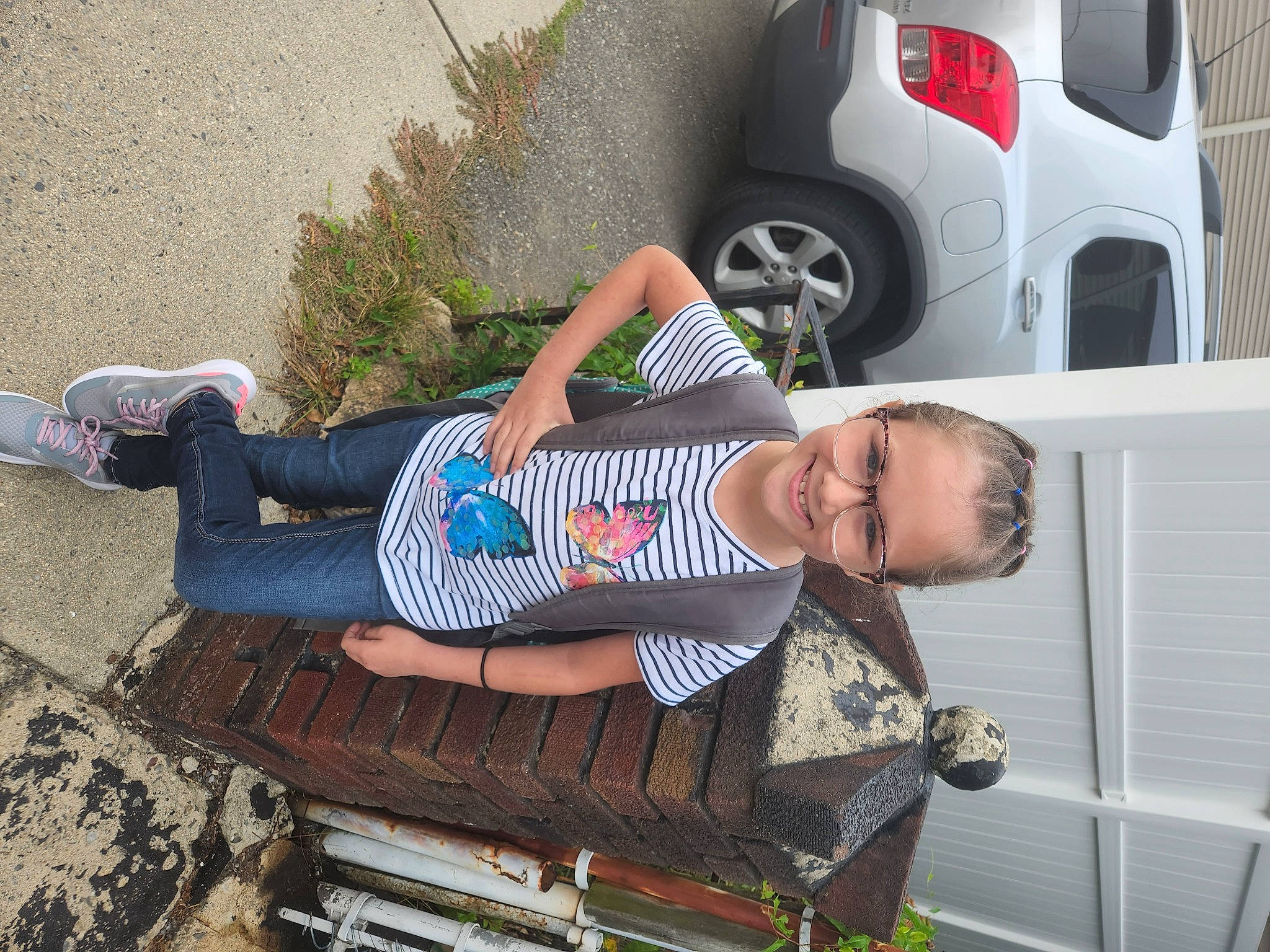 Lacie is registered to the contest to win money with this photo: automotive_design, automotive_exterior, automotive_lighting, automotive_tire, baby_toddler_clothing, car, fender, human_leg, joy, motor_vehicle, outdoor_bench, outdoor_furniture, pattern, person, sandal, sidewalk, thigh, tire, toddler, vehicle