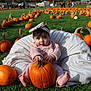 baby, pumpkin, pumpkin_patch, grass, beanbag, child, outdoor, fall, autumn, festival, headband, pink_clothing, barefoot, people, nature, cute, orange, green_grass, daylight, curious