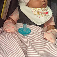 Justice is registered to the contest to win money with this photo: adorable, baby, bib, blanket, car_seat, child, cute, hat, indoors, infant, mittens, pacifier, peaceful, pink_clothing, portrait, resting, seatbelt, sleeping, soft_lighting, striped_blanket