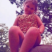 Oaklynn is registered to the contest to win money with this photo: child, girl, outdoor, nature, trees, sky, rock, smiling, sitting, sparkly_clothing, gold, barefoot, portrait, young, casual, daylight, happy, cute, playful, fun