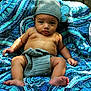 Zaqurian is registered to the contest to win money with this photo: baby, child, crochet, hat, diaper_cover, blue_blanket, patterned_blanket, outdoor, wooden_fence, skin, barefoot, sitting, portrait, curious, expression, natural_light, infant, cute, plush, texture