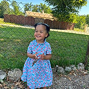 Lena a rejoint le concours — aidez-le/la à gagner de superbes lots ! child, girl, smiling, outdoor, dress, keys, fence, grass, tree, rocks, sunny, happy, footwear, sandals, curly_hair, playful, nature, daylight, portrait, cute