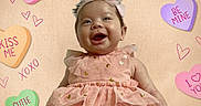 Talitha is registered to the contest to win money with this photo: baby, girl, pink_dress, headband, smiling, happy, face, child, valentine, hearts, candy_hearts, text, background, cute, portrait, infant, dress, celebration, love, colorful
