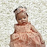 Talitha joined the competition — help win amazing prizes! baby, infant, dress, headband, bow, flower_background, peach_color, butterfly_pattern, cute, portrait, soft_texture, child, adorable, smiling, young, lying_down, pretty, fashion, closeup, toddler