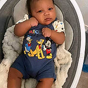 Yo'Shon is registered to the contest to win money with this photo: baby, infant, child, mickey_mouse, donald_duck, pluto, cartoon_characters, onesie, baby_seat, blanket, indoor, cute, portrait, expression, furniture, floor, clothing, person, resting, casual