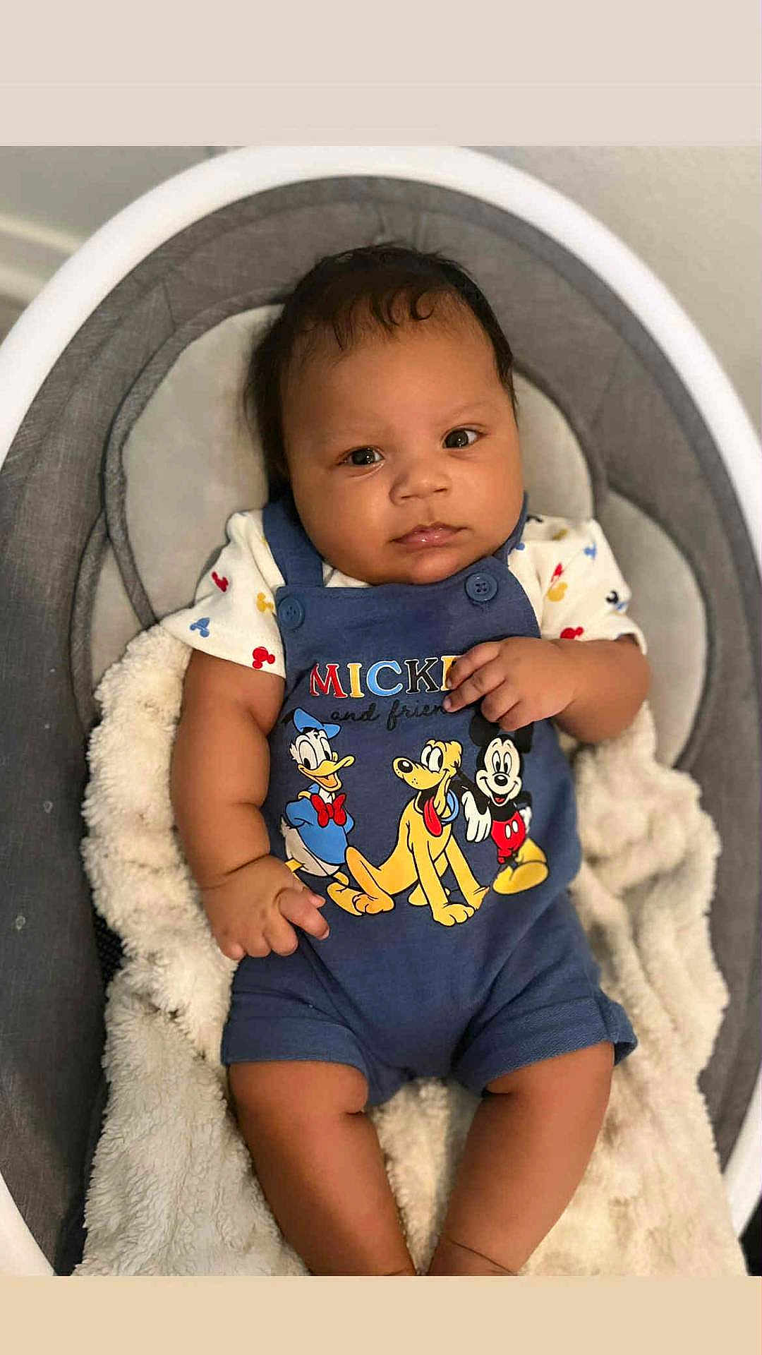 Yo'Shon is registered to the contest to win money with this photo: baby, infant, child, mickey_mouse, donald_duck, pluto, blue_outfit, baby_seat, blanket, cute, portrait, smiling, indoor, soft_lighting, clothing, person, young_child, baby_boy, sitting, cozy