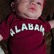 Aubree is registered to the contest to win money with this photo: baby, bow, casual, child, closeup, curious, cute, expression, fabric, face, headwear, indoors, infant, lying_down, maroon_clothing, person, portrait, pouty, soft_lighting, young