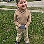 child, boy, smiling, grass, lawn, gloves, sweater, pants, sneakers, suburban, house, car, sidewalk, tree, outdoor, street, playful, person, portrait, casual