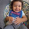 Legend is registered to the contest to win money with this photo: toddler, baby, smiling, curly_hair, bib, bottle, sitting, child, indoor, cushion, patterned, clothing, happy, face, person, cute, young_child, infant, holding, comfort