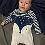 baby, child, infant, onesie, striped_clothing, plush_animal, bed, blanket, sleepwear, face, person, cute, smiling, young, indoors, soft_lighting, comfort, lying_down, blue, white