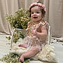 Elizabeth joined the competition — help win amazing prizes! baby, infant, child, toddler, dress, headband, flower, floral_arrangement, smile, sitting, studio_backdrop, curtain, blanket, soft_texture, tutu, curly_hair, barefoot, portrait, props, decor