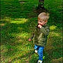 child, grass, tree, jacket, jeans, shoe, outdoor, nature, daylight, house, greenery, casual_clothing, young_boy, standing, sunlight, shadow, leafy, yard, curious, portrait