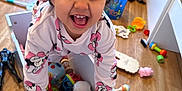 Arya a rejoint le concours — aidez-le/la à gagner de superbes lots ! child, toddler, smiling, curly_hair, toy_box, toys, indoor, hardwood_floor, pajamas, minnie_mouse, laughing, excited, face, hands, playroom, storage_box, colorful, floor, bucket, portrait