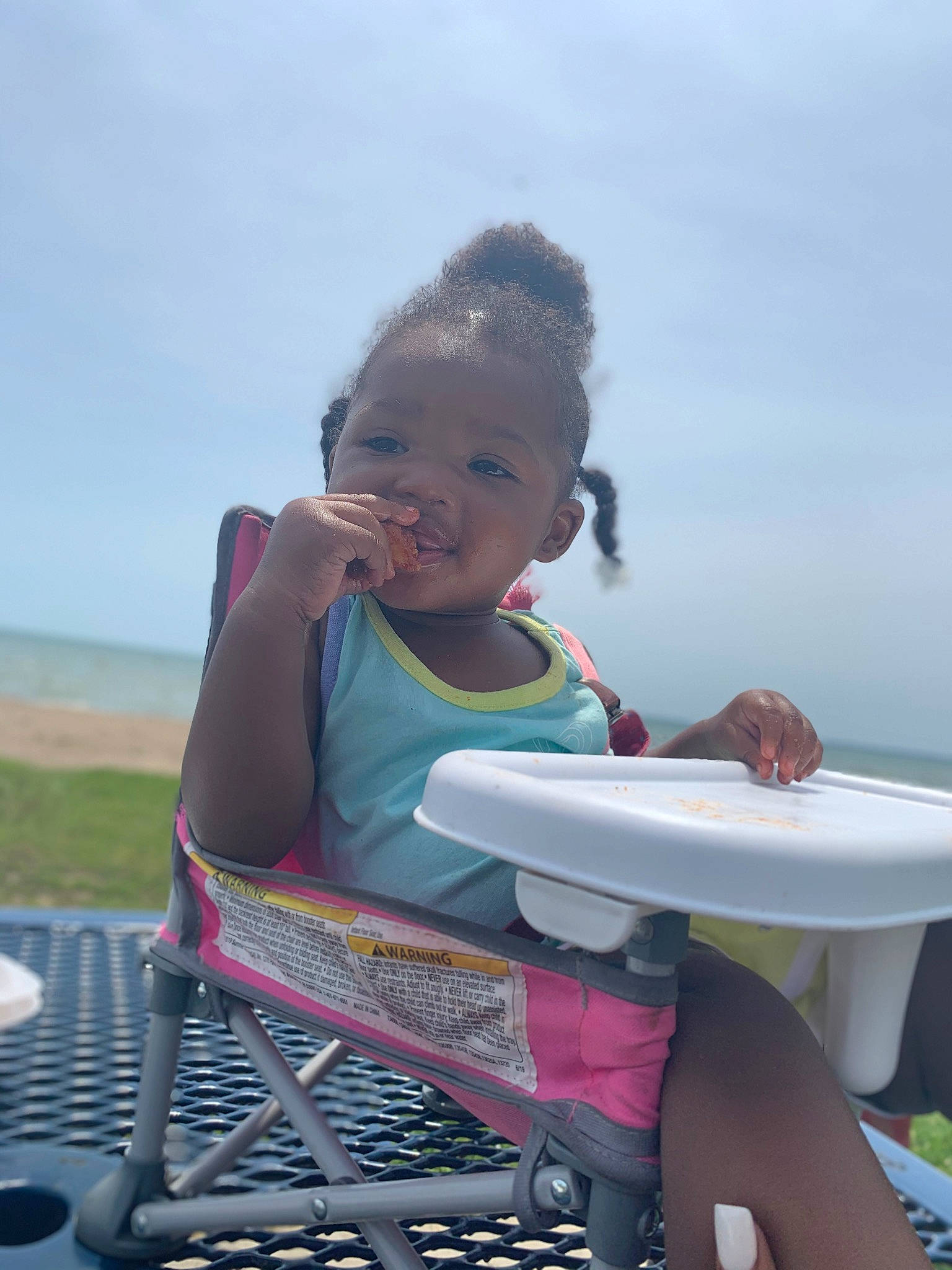 Ramona is registered to the contest to win money with this photo: baby_products, chair, child, fun, grass, happy, leisure, ocean, person, personal_protective_equipment, play, recreation, sitting, sky, smile, toddler, toy, travel, vacation, water