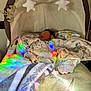baby, sleeping, bassinet, blanket, stars, soft_toys, rainbow_light, cozy, indoor, child, infant, nursery, fabric, toddler, cute, peaceful, sleep, colorful, pattern, resting
