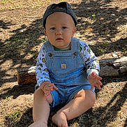 Lucas is registered to the contest to win money with this photo: child, toddler, baby, overalls, cap, barefoot, grass, sunlight, shadow, outdoor, log, fence, curious, sitting, nature, clothing, face, person, summer, playful